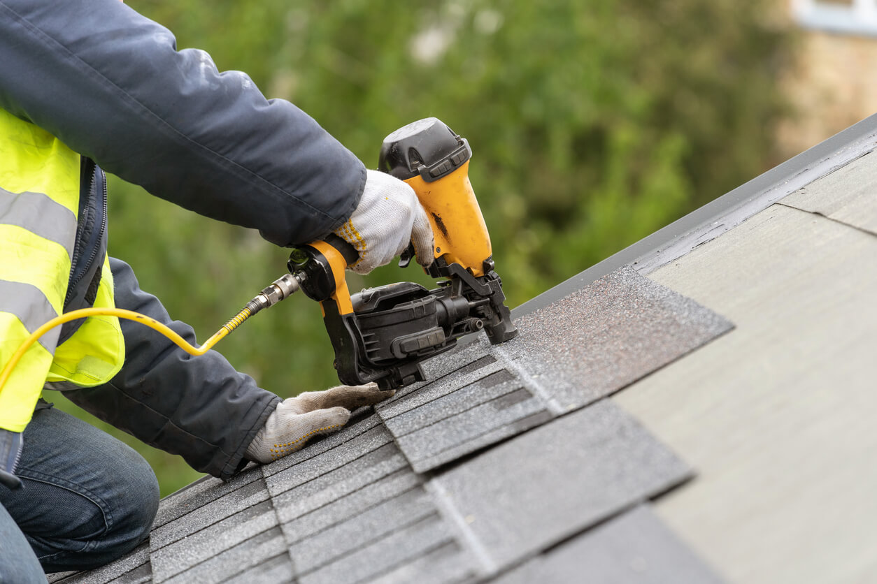 A guy repairing roof shingles